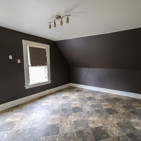 Outdated primary bedroom with tile floor and slanted roof