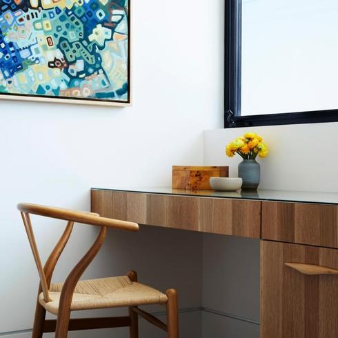 Simple home office with modern desk under a window and a wishbone chair