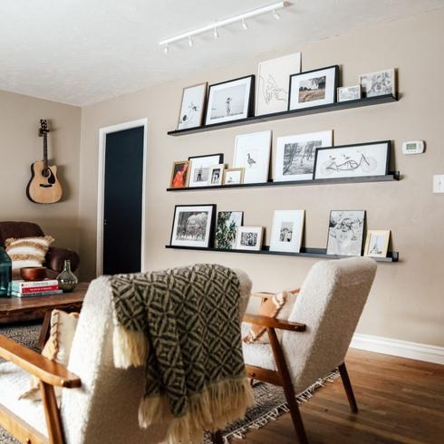 A photo ledge mounted on the wall with several different frames.