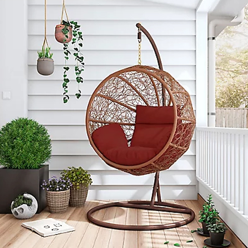 A round egg chair with red cushions.