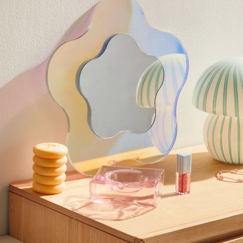 A flower-shaped mirror on a dresser.