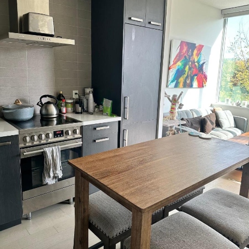 An open concept kitchen, dining and living area with dark wooden cabinetry and a large window