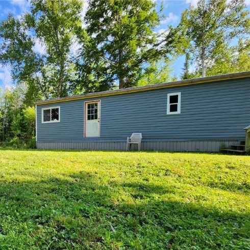 A small single level house with blue siding and white-framed door and windows