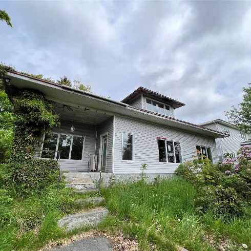 A house on a hillside with grey siding and decorative eaves