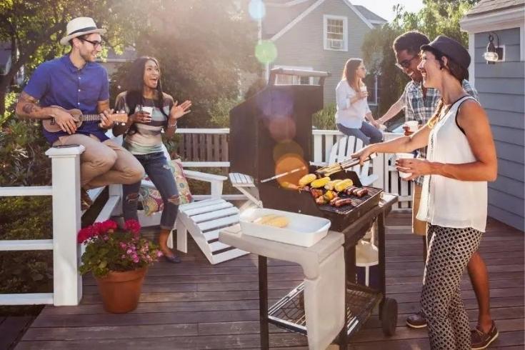 A group of friends grilling veggies on a porch in the summer. 