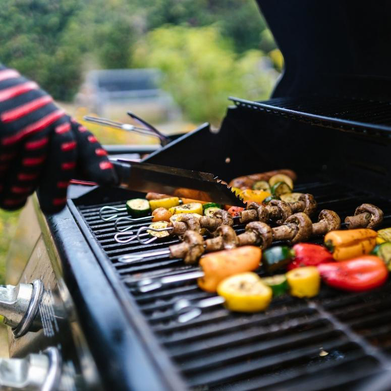A person grilling vegetables on a BBQ