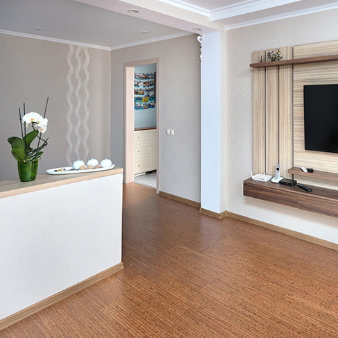 Small white apartment with cork flooring and a large TV hung on the wall as part of a home reno trends story for Home Network