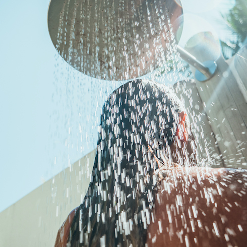 Low angle view of a woman in an outdoor rain shower as part of a home reno trends story for Home Network