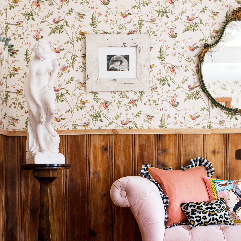 A shot of the details in The Roadhouse's front room, including a pink velvet chaise and vintage wallpaper and wainscotting