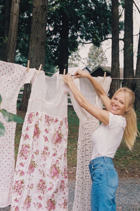 Pamela Anderson wearing a white t-shirt and jeans hanging up laundry