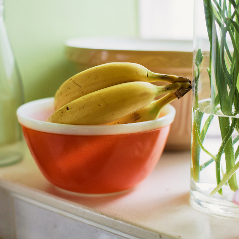 Bananas sit in a paprika-coloured vintage Pyrex bowl