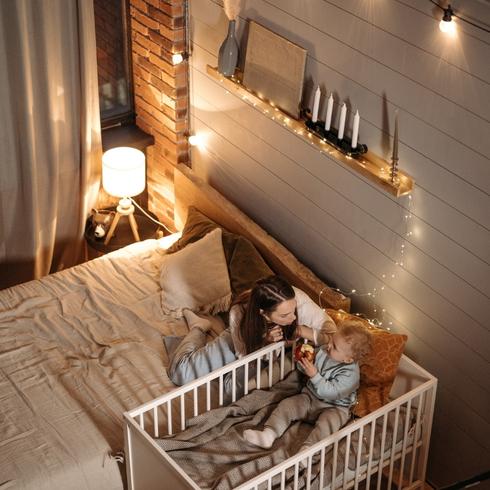 A mom playing with a baby in her crib.