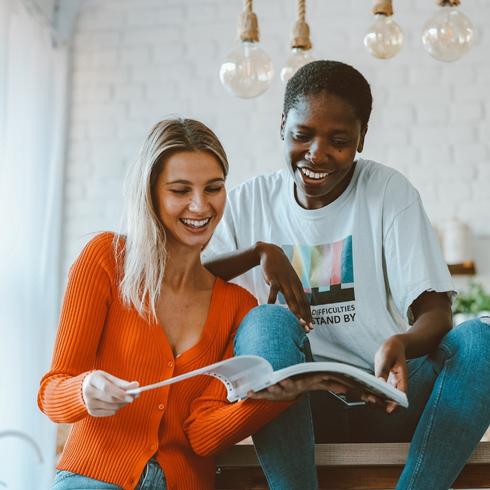 Two friends reading a magazine in a kitchen