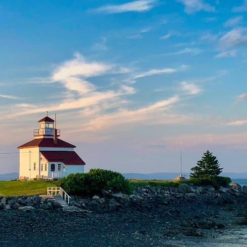 A lighthouse on a hill overlooking the ocean in Gilbert's Cove, Nova Scotia