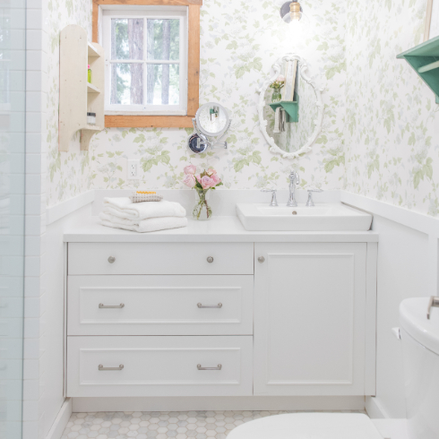 The new bathroom at The Cabin, with green floral wallpaper and white cabinetry