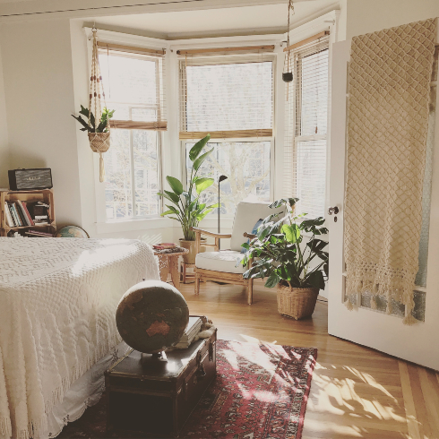 A bedroom with a bay window, a seating area with a chair, and a bed