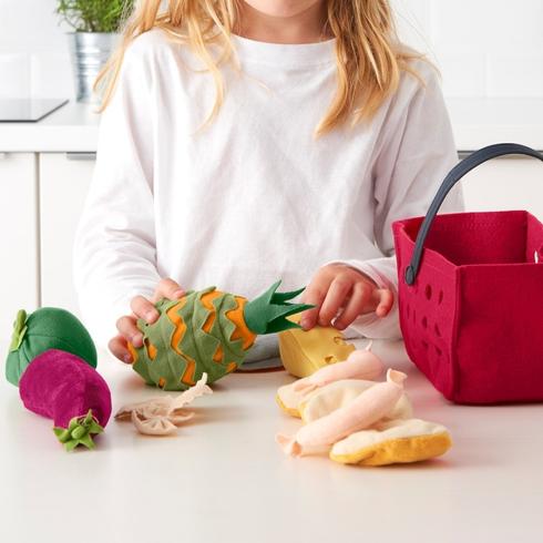 A kid playing with fake veggies