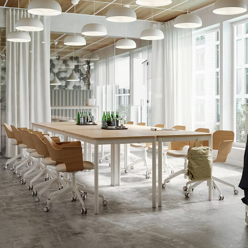 A wooden topped desk with many office chairs around it