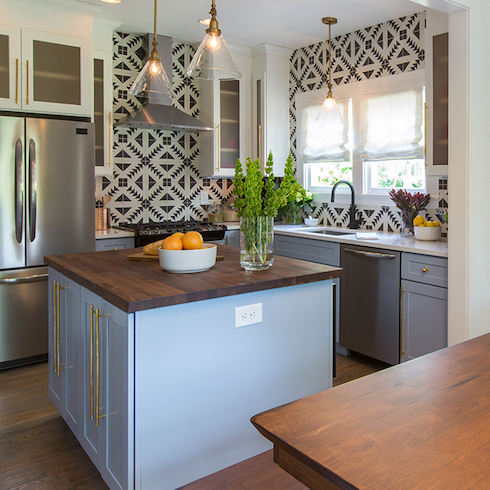 Stunning modern kitchen designed by Home Network’s Property Brothers featuring a blue kitchen island and a graphic tile backsplash that goes up to the ceiling