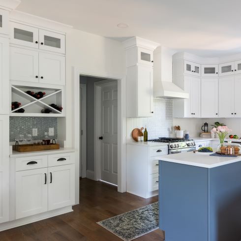 Intricate all white kitchen cabinets and a small light blue island