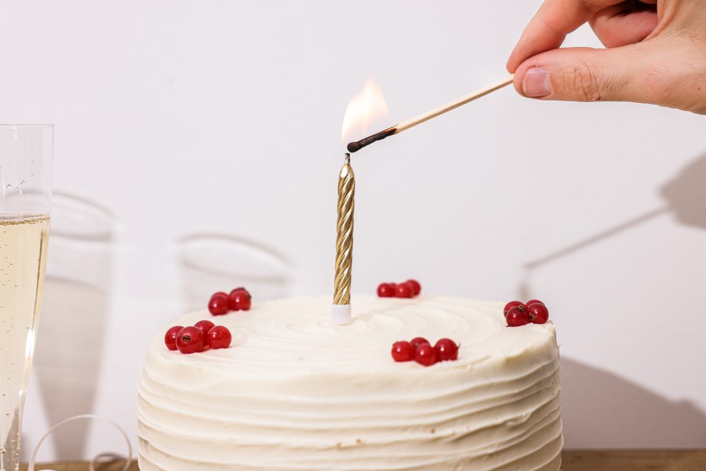 Person lighting candle on cake 