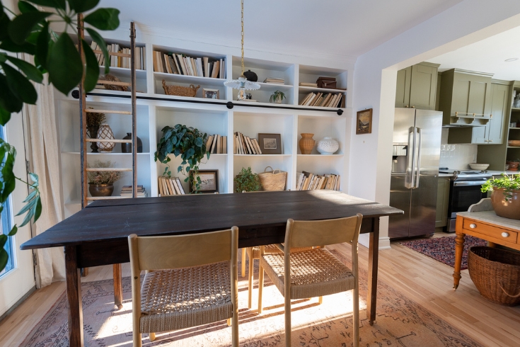 A dining room with large table with four chairs and built-in bookcases along one wall