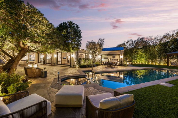 A saltwater swimming pool surrounded by a flagstone deck and lounge furniture