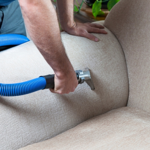 Man steam-cleaning his sofa