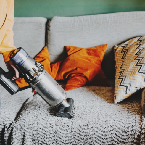 Person using-vacuum-cleaner-on-the-sofa