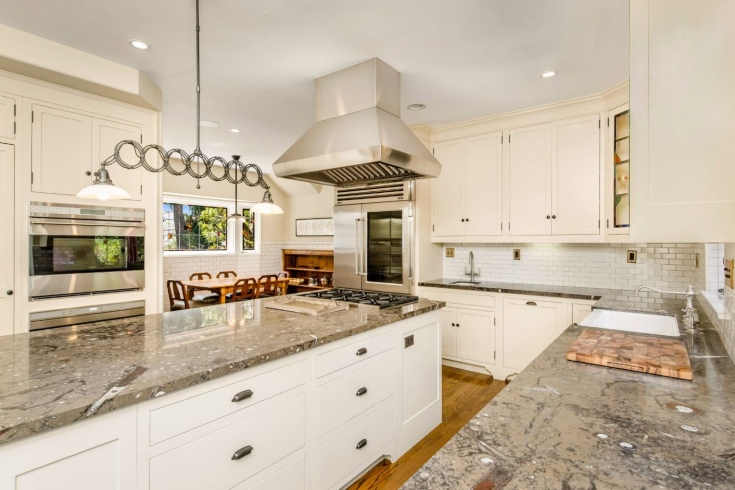 A large kitchen with stainless steel appliances, marble counters, a centre island, and a casual dining area