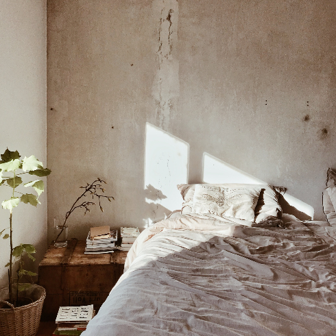 A neutral bedroom with a tan textured wall in the morning light