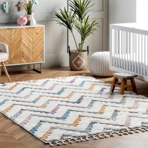 Nursery baby nursery room with soft blue and yellow area rug.