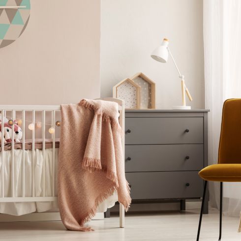 Neutral nursery room with crib and grey dresser