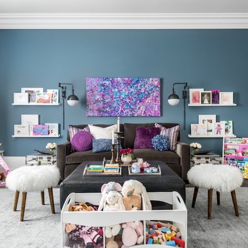 Storage-filled playroom with moody blue walls and built-in white shelving designed by Scott McGillivray for his daughters as part of an Home Network renovation show