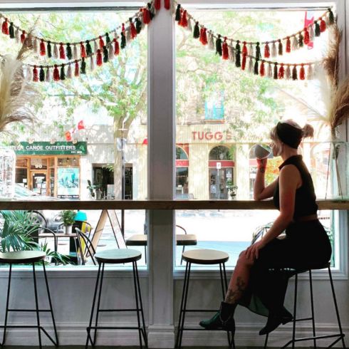 A woman enjoying coffee by the window at Change Makers Refillery.