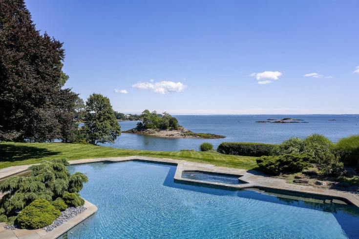 A large outdoor swimming pool and spa tub overlooking the ocean