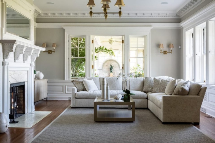 A living area with light-hued furnishings, neutral-toned walls, a fireplace and large windows.