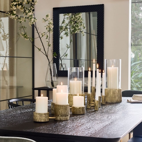 Metal candle holders with various sized candles on a tabletop