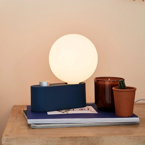 A blue aluminum table lamp with a globe-style bulb