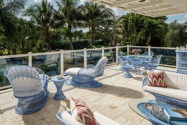 A patio with assorted seating and side tables overlooking palm trees