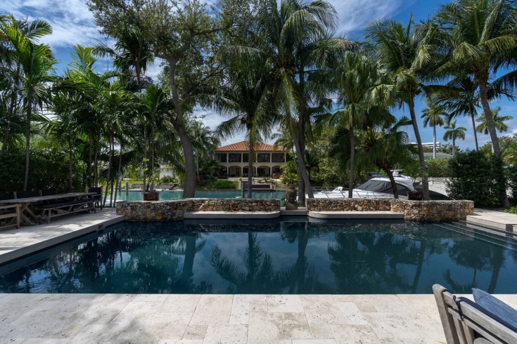 A swimming pool with palm trees and a house in the background