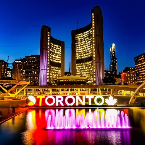 Toronto's City Hall at night with the colourfully-lit Toronto sign