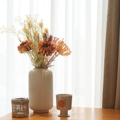 Bright room with vase filled with faux flowers on wooden table