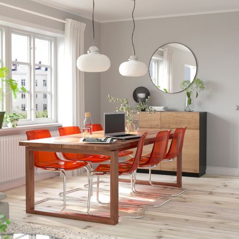 Dining room with grey walls, large wood dining table and bright red chairs.