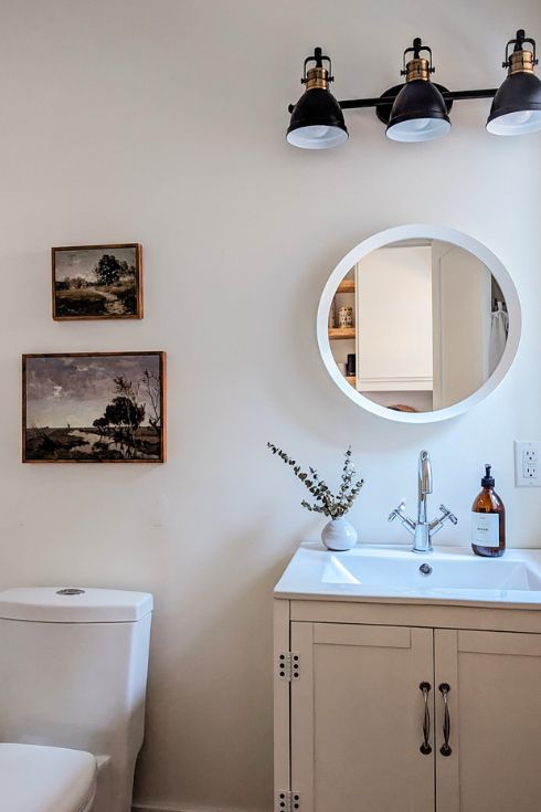Modern white bathroom with vintage-inspired art above toilet