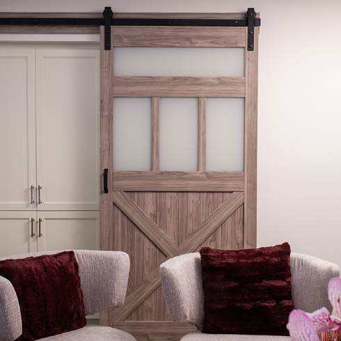 A sliding barn door covers a white cabinet area