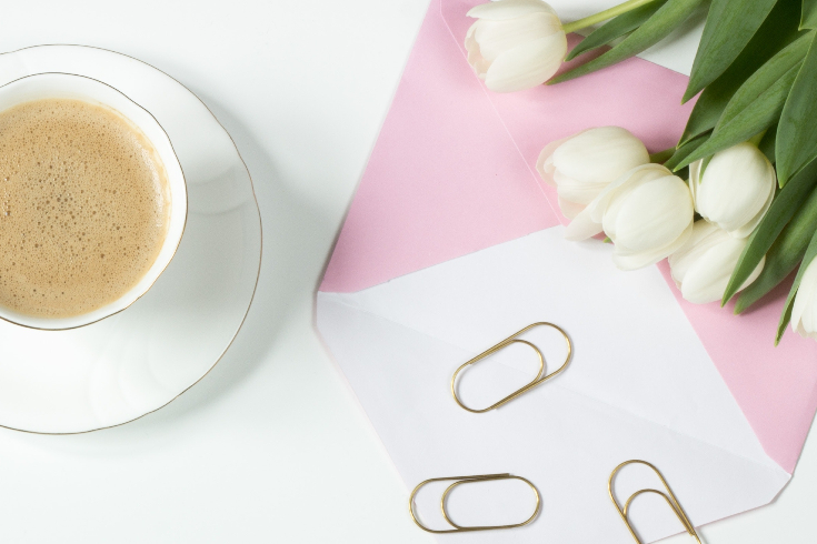 A coffee cup with an envelope and paperclips