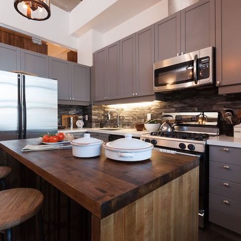 Luxe-looking details in a gorgeous kitchen with mid-tone wood island, marble backsplash and end walls encased in stainless steel in a kitchen renovation designed by Scott McGillivray for Home Network