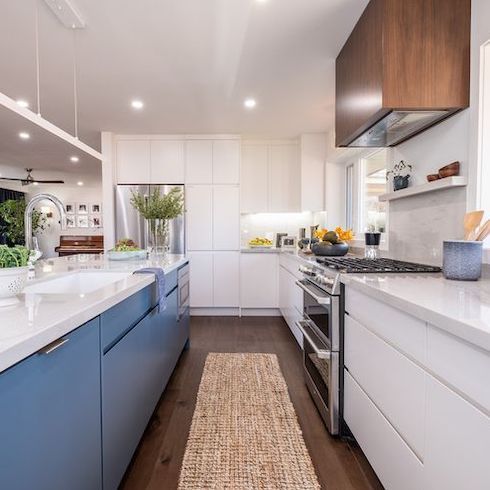 Jonathan and Drew Scott designed and built this kitchen renovation for Home Network’s Property Brothers: Forever Home and features white floor to ceiling cabinetry, a blue kitchen island, and a hidden small appliance garage for a super minimalist kitchen design