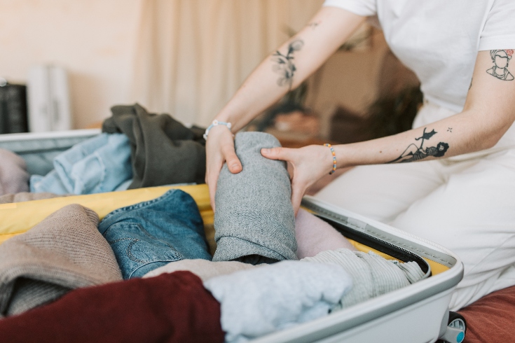 A person placing items into a suitcase.